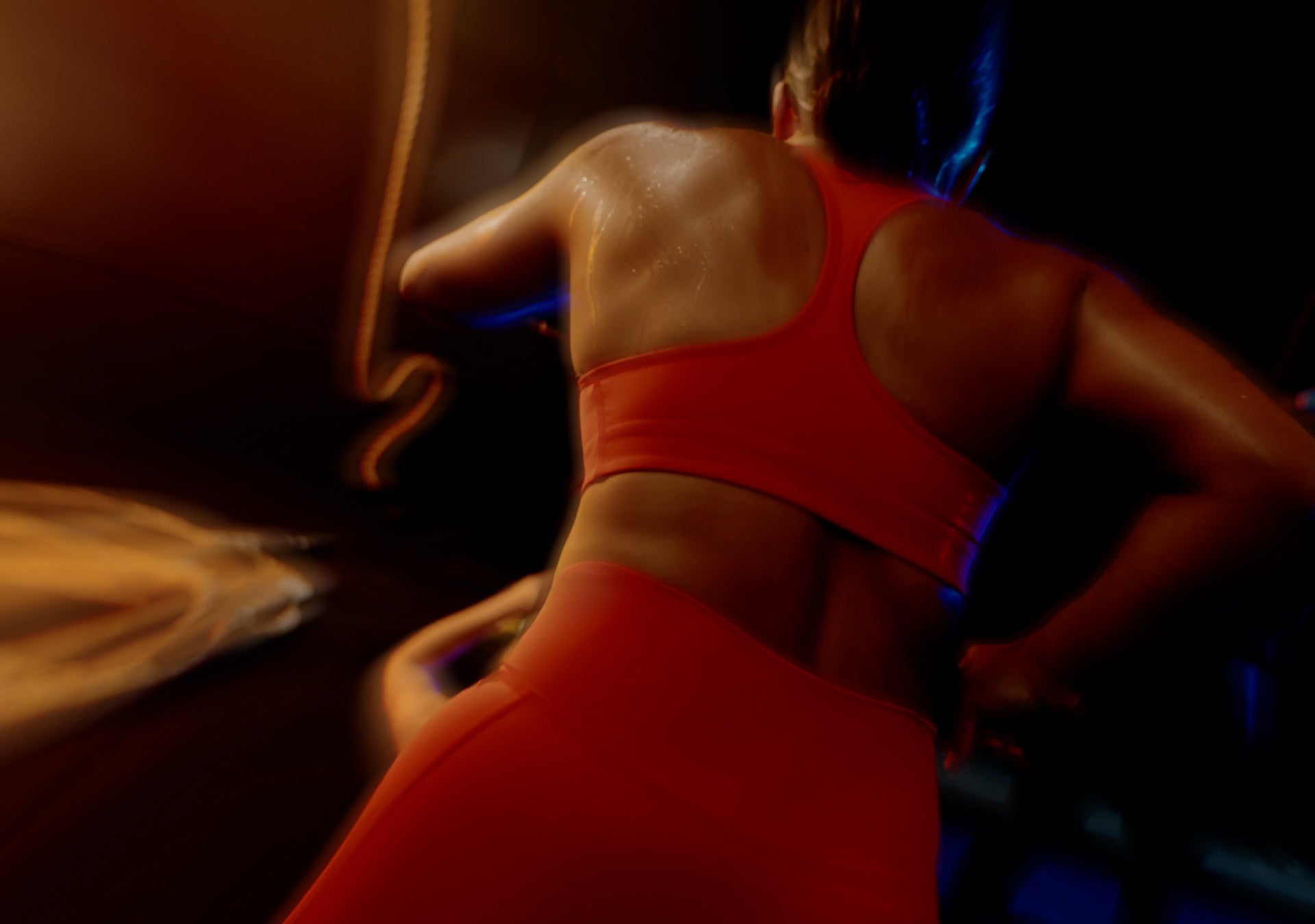 Person wearing a red sports bra and shorts in a dark setting